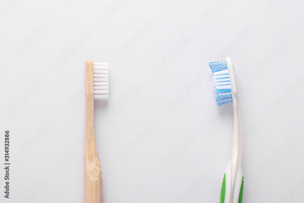 Zero waste concept, Eco wooden toothbrush vs plastic toothbrush on white background: Reduce, Reuse and Recycle concept. Flat lay, Closeup, Horizontal orientation
