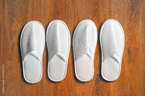 Top view two pairs of new soft white slipper in the hotel on wooden floor. Four white slipper, Isolated on wooden floor. Top view. 