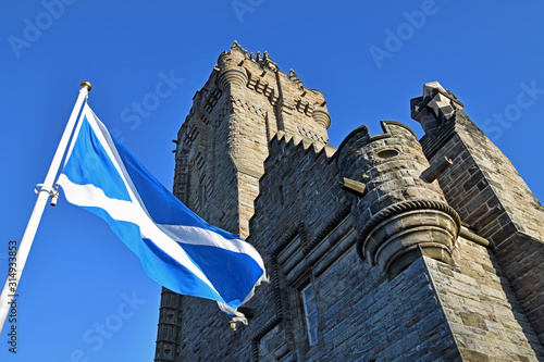 Wallace Monument in Stirling, Scotland with Scotttish flag (St Andrews Cross) flying in foreground