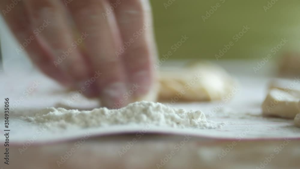 unrecognizable woman is heaping round pieces of a dough in a flour for making dumplings, 4K close-up unrecognizable woman is heaping round pieces of a dough in a flour for making dumplings, 4K close-up