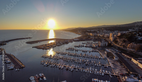 Dramatic sunset over the mediterranean sea in El Maresme Coast. Aerial panoramic view of Arenys de Mar harbor at dawn. photo