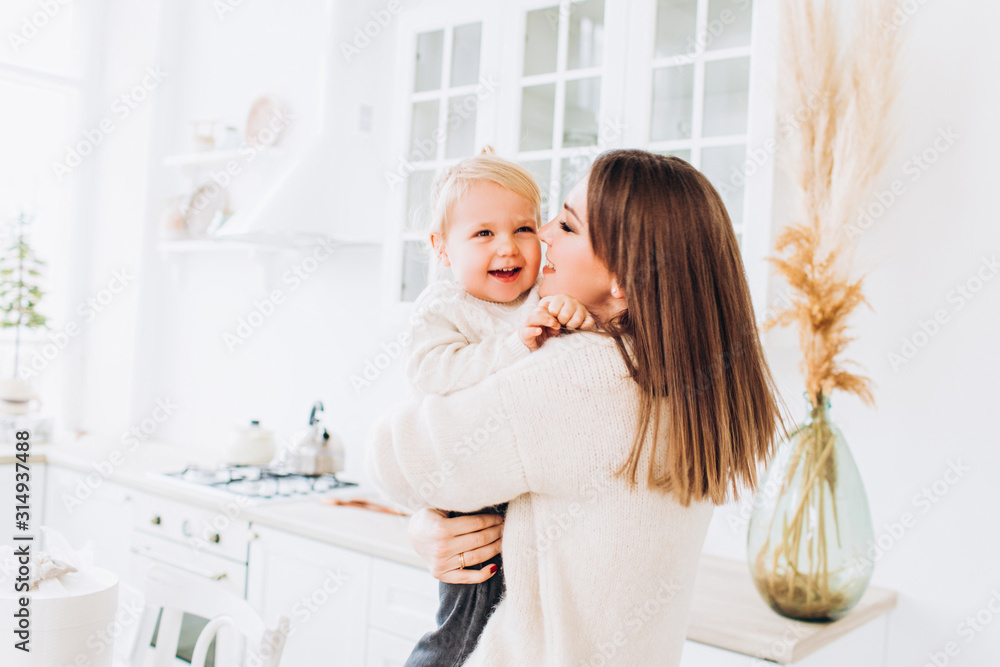 Mom and daughter in the kitchen in a bright apartment or house. Mom and daughter in the kitchen in a bright apartment or house.