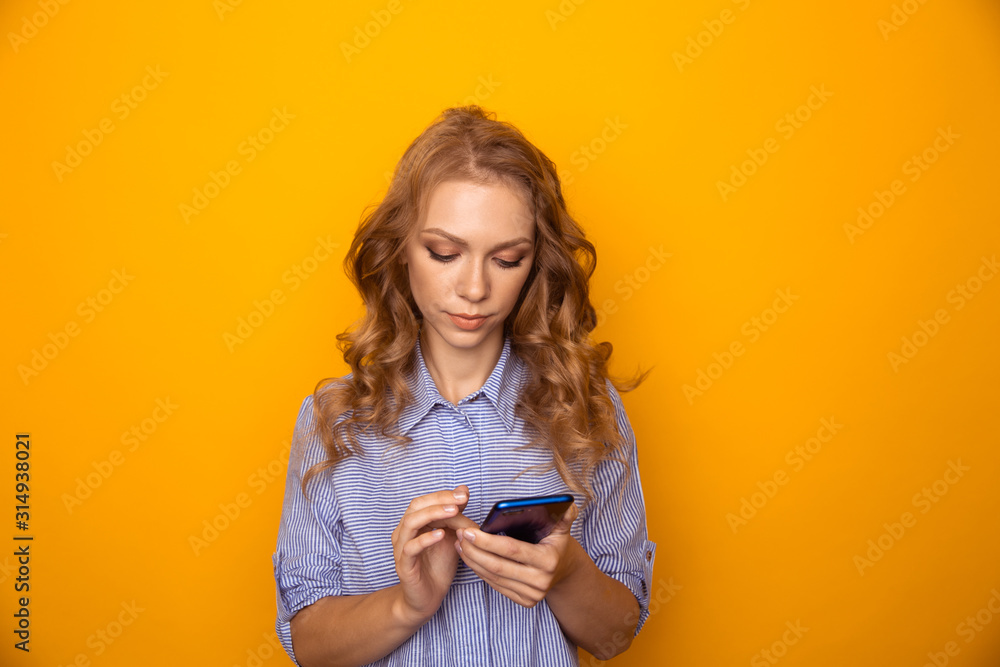 Young woman using phone standing isolaed in the yelow studio Young woman using phone standing isolaed in the yelow studio