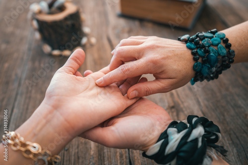 Tableau sur toile Close up of fortune teller point her finger to woman's palm line and read her fortune
