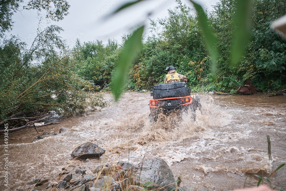 Quad rider jumping on a muddy forest trail. Quad rider jumping on a muddy forest trail.