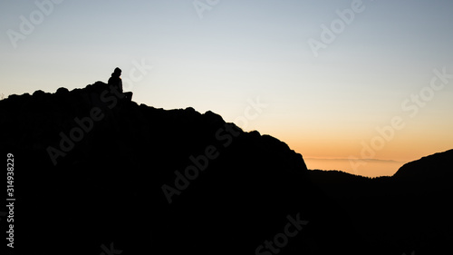 Silhouette of a person on the top of the mountain during sunset