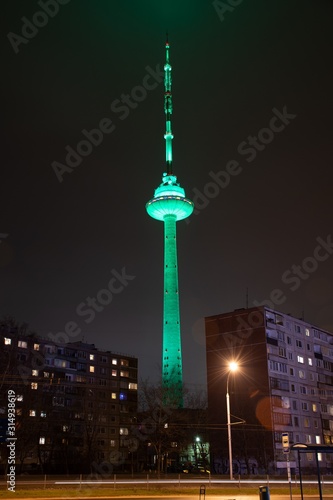 Vilnius TV Tower, Lithuania colored with green light, night with soviet buildings, vertical