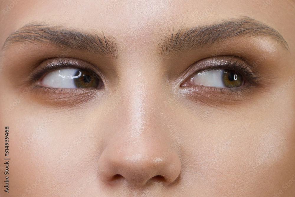 Fototapeta premium Close-up of woman's eyes with evening make-up. Fashionable shades of eye shadow, extremely long eyelashes and thick smooth eyebrows. Open beautiful look. Clean skin