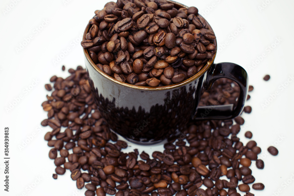 Fototapeta premium Close up on dark coffee mug overflowing with whole coffee beans