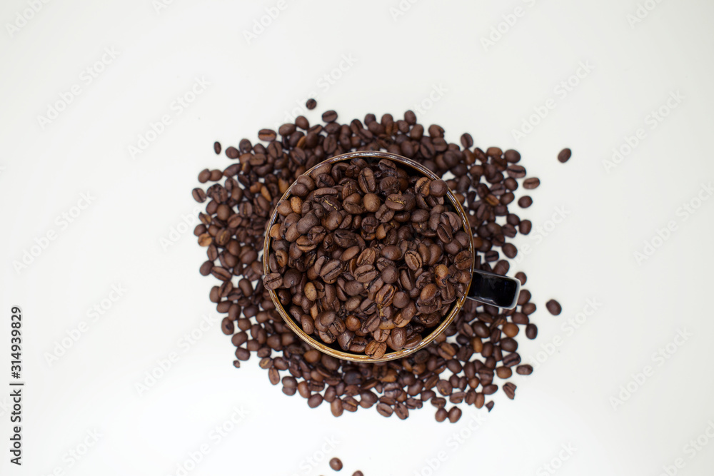 Close up on dark coffee mug overflowing with whole coffee beans Close up on dark coffee mug overflowing with whole coffee beans