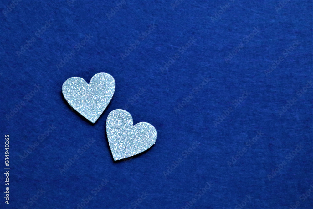 Obraz premium two silver hearts on classic blue background in trendy color of year. Copy space.