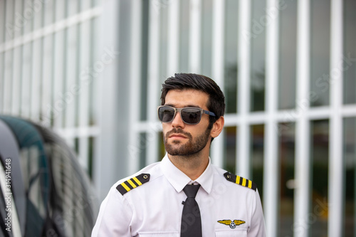 Confident Helicopter pilot standing by the vehicle at Airport terminal