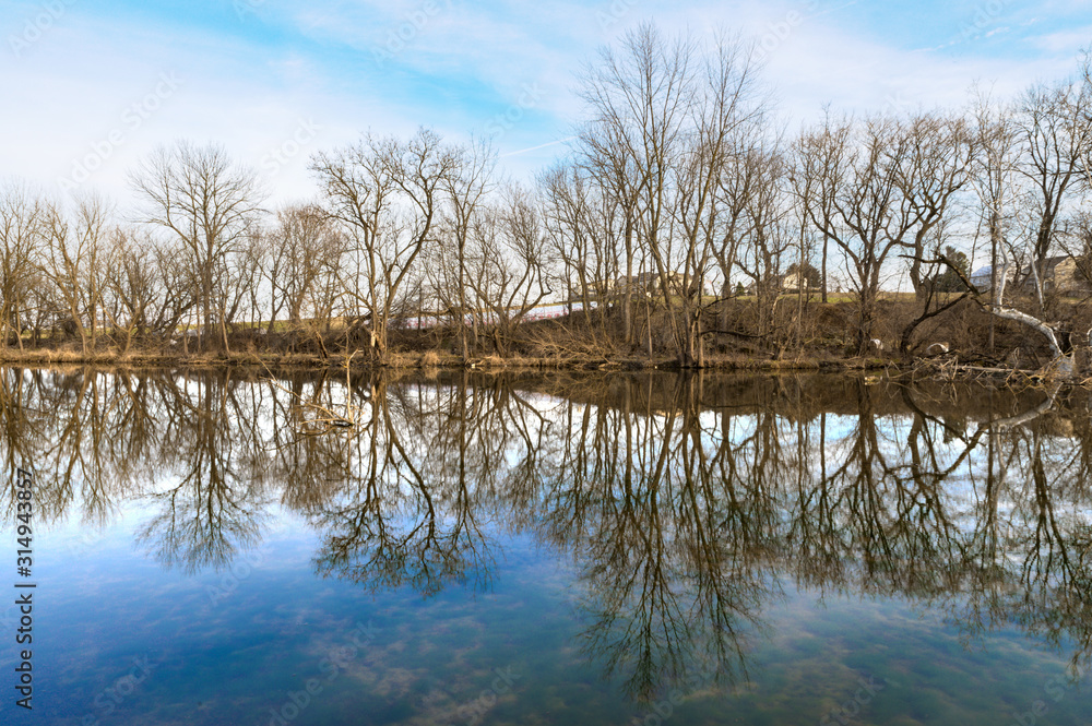 Leafless trees reflect in a mirrorlike lake on a cold winter's day, Lancaster County, Pennsylvania