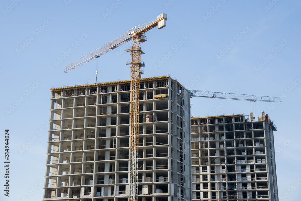 Hydraulic luffing jib tower cranes and workers being poured concrete into foundation. Cement pouring into formwork of building at construction site. Tower cranes constructing a new residential build Hydraulic luffing jib tower cranes and workers being poured concrete into foundation. Cement pouring into formwork of building at construction site. Tower cranes constructing a new residential build