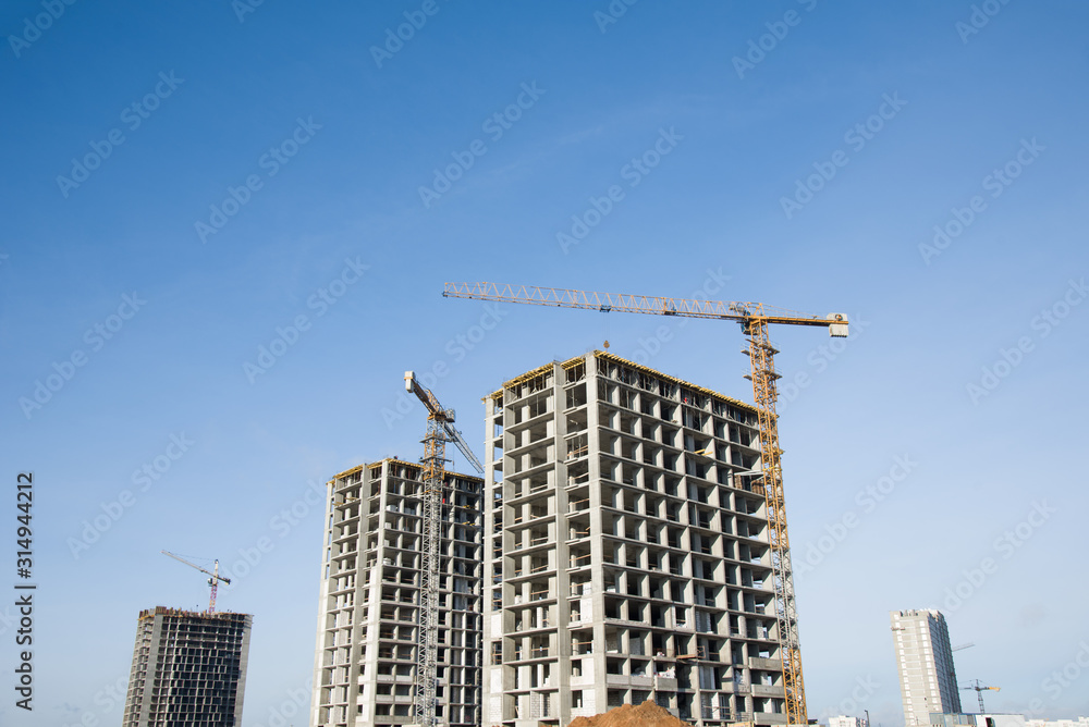 Hydraulic luffing jib tower cranes and workers being poured concrete into foundation. Cement pouring into formwork of building at construction site. Tower cranes constructing a new residential build Hydraulic luffing jib tower cranes and workers being poured concrete into foundation. Cement pouring into formwork of building at construction site. Tower cranes constructing a new residential build