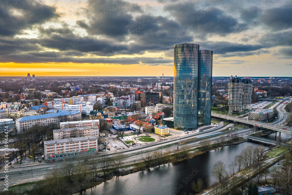 Aerial view over Riga city in colorful sunset. Urban landscape with skyscrapers and highway. 