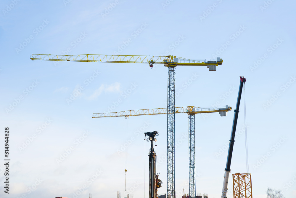 Hydraulic luffing jib tower cranes and workers being poured concrete into foundation. Cement pouring into formwork of building at construction site. Tower cranes constructing a new residential build Hydraulic luffing jib tower cranes and workers being poured concrete into foundation. Cement pouring into formwork of building at construction site. Tower cranes constructing a new residential build