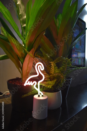 neon flamingo sitting by a plant
