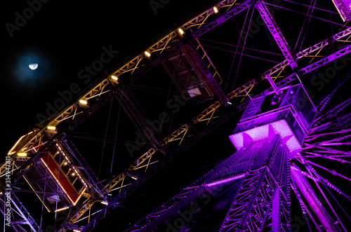 Night view of a Big Wheel lit with pink violet and golden lights