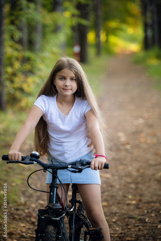 Obraz premium Little girl having fun on bike in the forest in autumn season