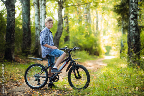 Teen boy rides a bicycle along a path in the forest. The cyclist rides fast through the springboards.