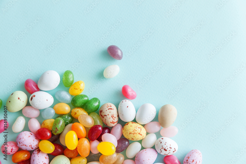 Happy Easter concept. Preparation for holiday. Easter candy chocolate eggs and jellybean sweets isolated on trendy pastel blue background. Simple minimalism flat lay top view copy space. Happy Easter concept. Preparation for holiday. Easter candy chocolate eggs and jellybean sweets isolated on trendy pastel blue background. Simple minimalism flat lay top view copy space.