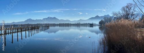 Foggy day on Chiemsee Lake in Bavaria - hut and mountains reflecting in water