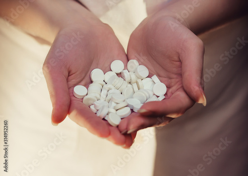 A handful of white pills in female hands.