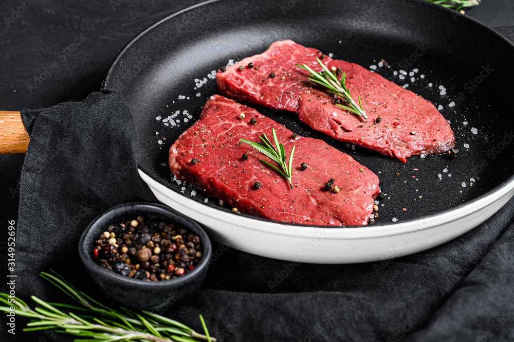 Raw Sirloin steak in a frying pan. Beef meat. Black background. Top view