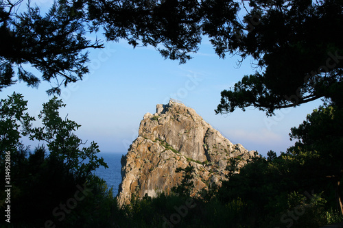 Stone rock in the light of the sun on a background of sky and sea