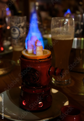 One feuerzangenbowle on fire with burning sugar, on a dining table at a Christmas party. A German tradition.
