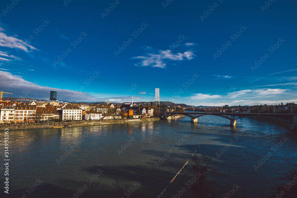 View on Basel city and river Rhine, Switzerland. Heritage, beautiful. Swiss city Basel in sunny weather in winter. View of the embankment and the river Rhine, in which people walk and relax
