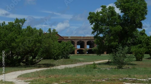Wide steady shot of the ruins of an old old fort framed by trees
