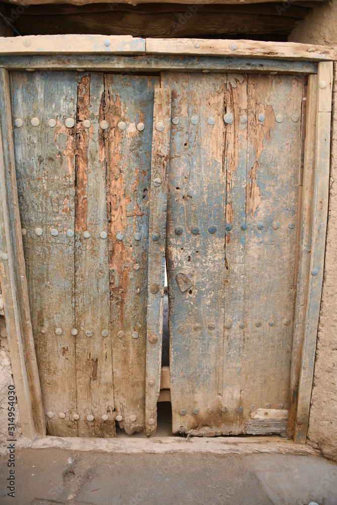 Eine geschlossene, altertümliche, verfallene Haustür in der verlassenen Stadt Al Hamra im Oman aus Holz. Eine geschlossene, altertümliche, verfallene Haustür in der verlassenen Stadt Al Hamra im Oman aus Holz.