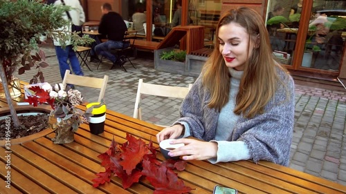 Girl sitting on the street and holding a cup of escrepreso in her hands 