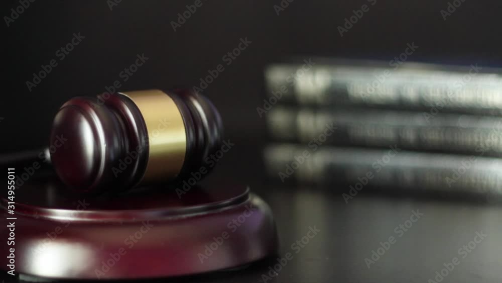 Judge hitting gavel three times on block with law books on the background Judge hitting gavel three times on block with law books on the background