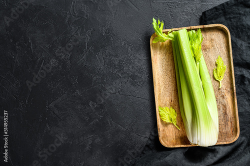 Bunch of fresh celery stalk with leaves. Black background. Top view. Space for text