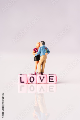 Love and Valentines Day concept: Miniature Couple with LOVE wordings on small beads on white backgrounds