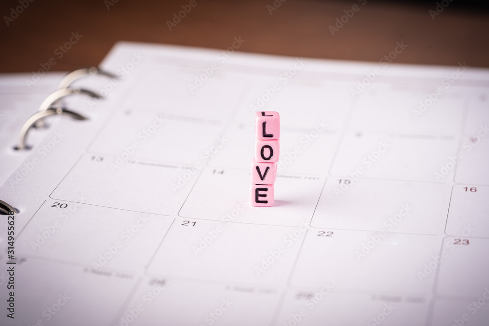 Love and Valentines Day concept: Miniature Couple with LOVE wordings on small beads on white backgrounds Love and Valentines Day concept: Miniature Couple with LOVE wordings on small beads on white backgrounds