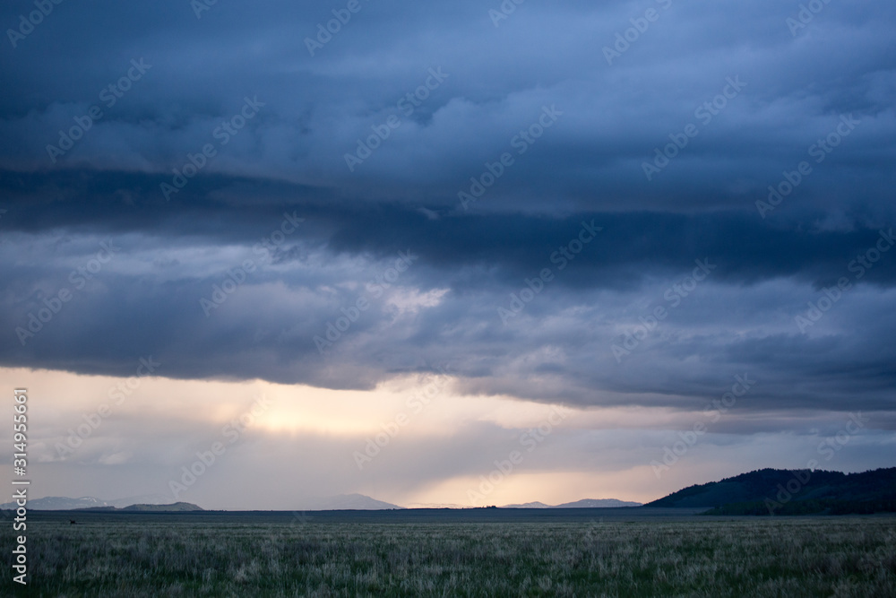 A storm passes over a field and mountains in Grand Teton National Park. 