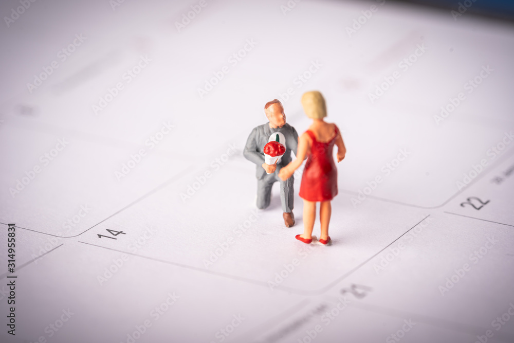 Love and Valentines Day concept: Miniature Couple with LOVE wordings on small beads on white backgrounds Love and Valentines Day concept: Miniature Couple with LOVE wordings on small beads on white backgrounds