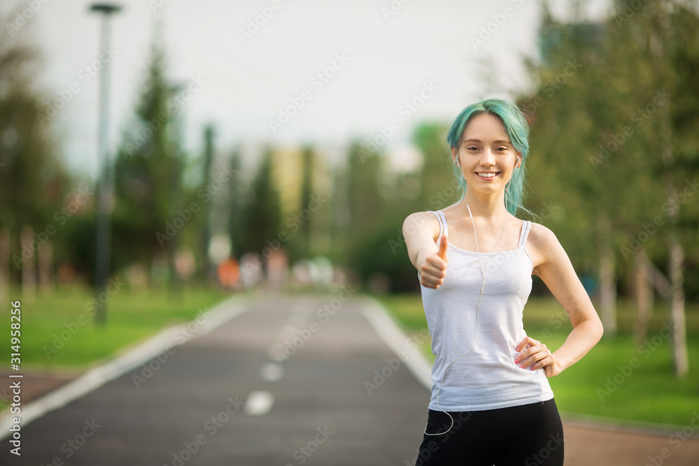 beautiful young woman with a slim figure is jogging in the summer in the park