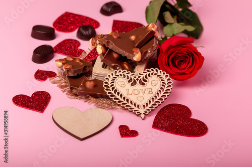 Valentine's day background with red hearts, chocolate candies and red rose on a pink background. Romantic atmosphere. Love symbols. photo