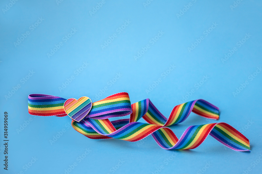 Bow from a rainbow ribbon with a rainbow heart on a blue background. Pride concept