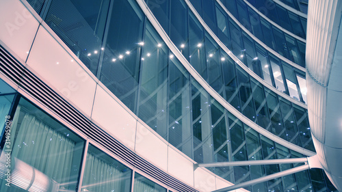 Night architecture - building with glass facade. Modern building in business district. Concept of economics, financial. Photo of commercial office building exterior. Abstract image of office building