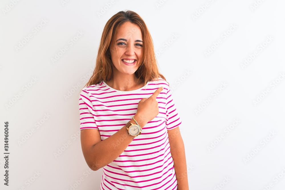 Young redhead woman wearing striped casual t-shirt stading over white isolated background cheerful with a smile of face pointing with hand and finger up to the side with happy and natural expression Young redhead woman wearing striped casual t-shirt stading over white isolated background cheerful with a smile of face pointing with hand and finger up to the side with happy and natural expression