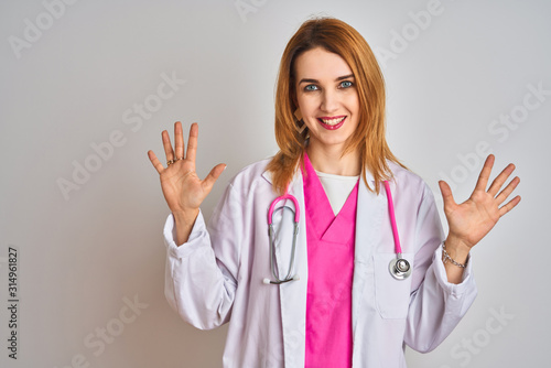 Redhead caucasian doctor woman wearing pink stethoscope over isolated background showing and pointing up with fingers number ten while smiling confident and happy.