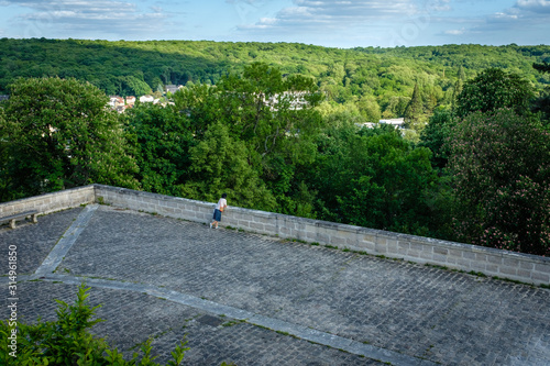 Woman calmly looking at the green forest from the viewpoint at a sunny day photo