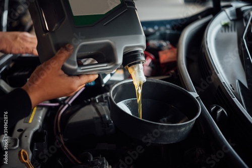 Car mechanic fills a fresh lubricant engine oil © pongmoji