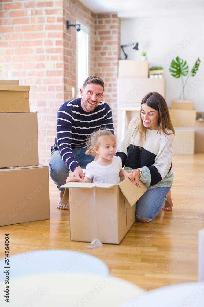 Beautiful famiily, kid playing with his parents riding cardboard fanny box at new home Beautiful famiily, kid playing with his parents riding cardboard fanny box at new home